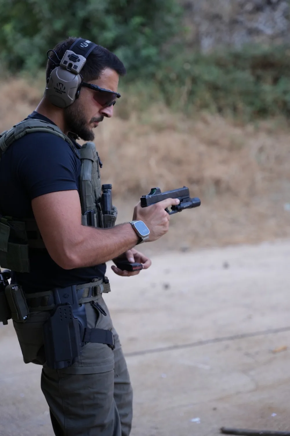An NES instructor reloading at the range, wearing ear and eye protection